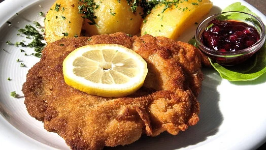 Zlatě opečený kuřecí řízek s citronem, bramborami a omáčkou.