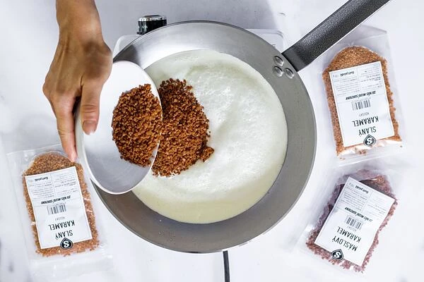 Přidávání hnědého cukru do pánve na výrobu domácího karamelu.