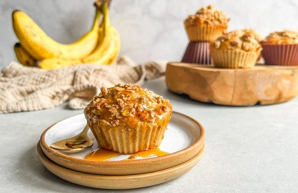 Banánový muffin s karamelovou polevou na talíři vedle banánu.