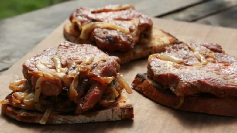 Připravené vepřové krkovice na toastu s cibulí.