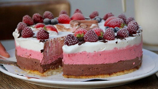 Nepečený cheesecake s ovocem na bílém talíři.