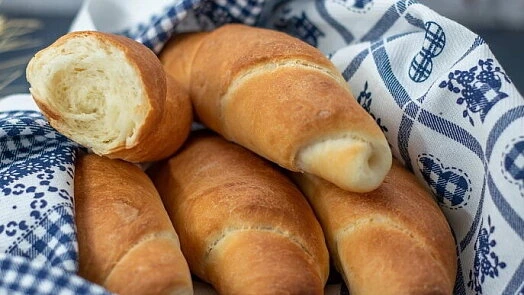 Zlatohnědé domácí rohlíky v košíku s odhalenou vrstvenou strukturou.