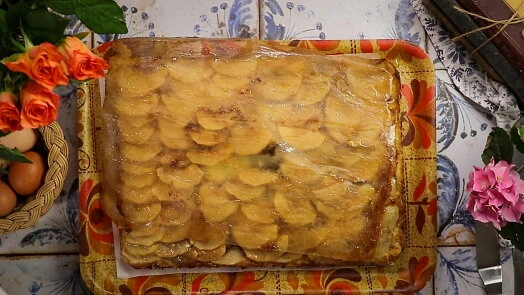 Hotový obrácený jablečný koláč na ozdobném podnosu.