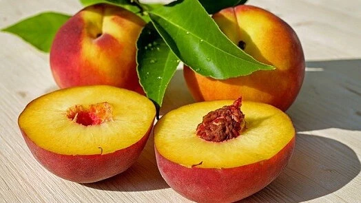 Čerstvé meruňky s listy na dřevěném povrchu