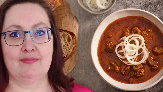 Žena s gulášem na talíři a chlebem vedle sebe.