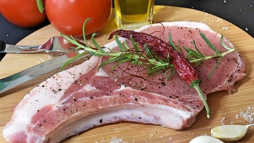 Surové vepřové kotlety s bylinkami na dřevěném prknu.