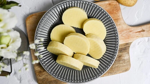 Na talíři jsou nakrájené uvařené brambory na knedlíky.